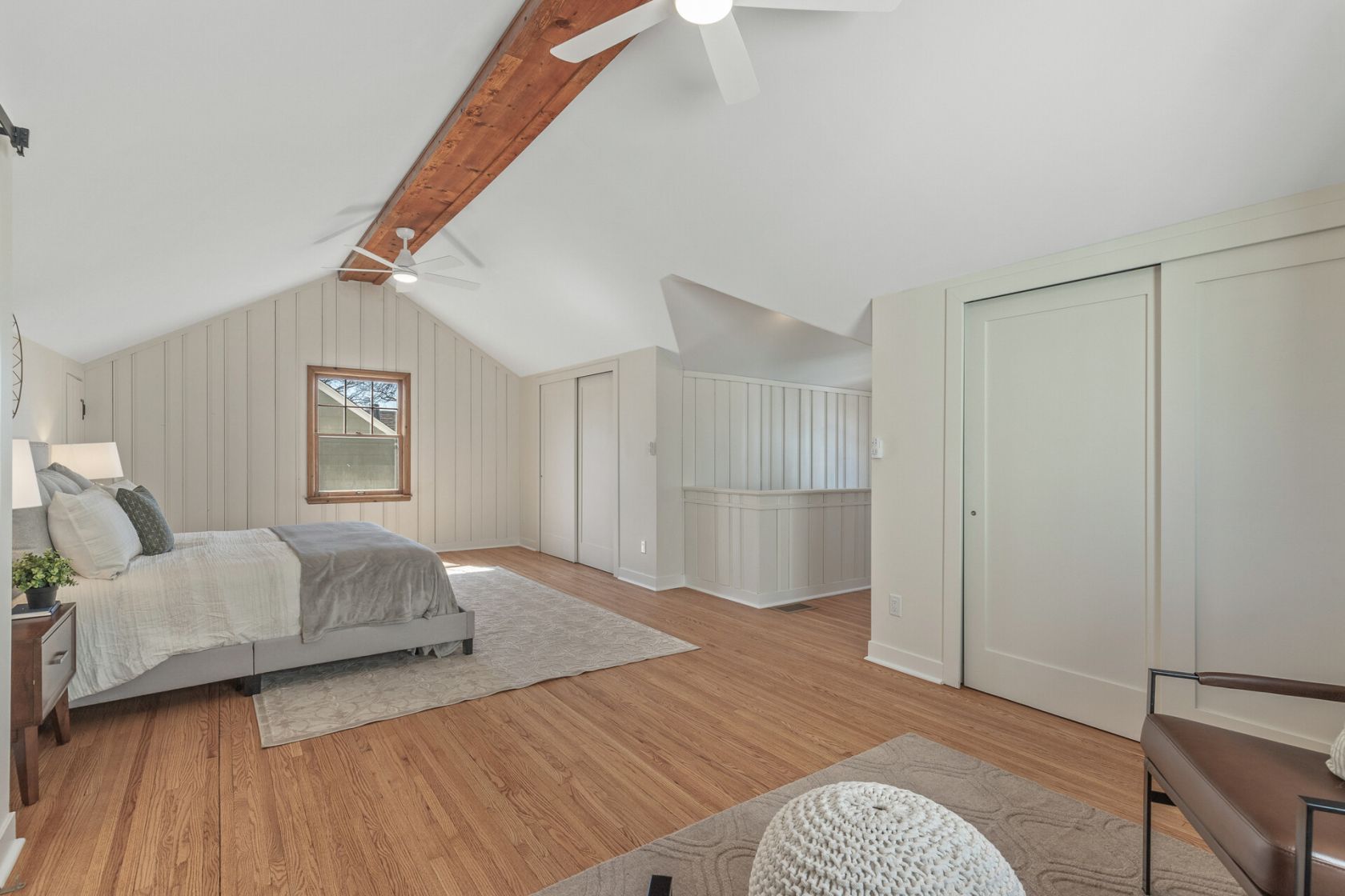 Vaulted primary suite with exposed beam and refinished oak floors